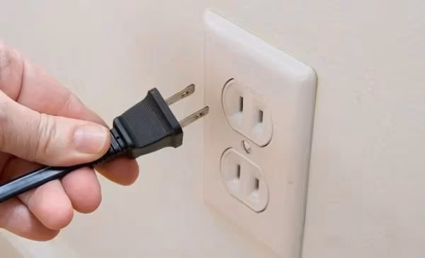 Unplugging Hisense TV power cable from wall outlet for power cycle